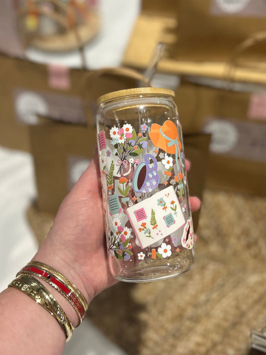 Hand holding a decorated glass jar with floral patterns, surrounded by brown paper bags.