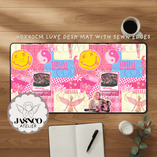 Pink and yellow 'Nirvana' themed desk mat on a wooden surface with a cup of coffee and notebook.